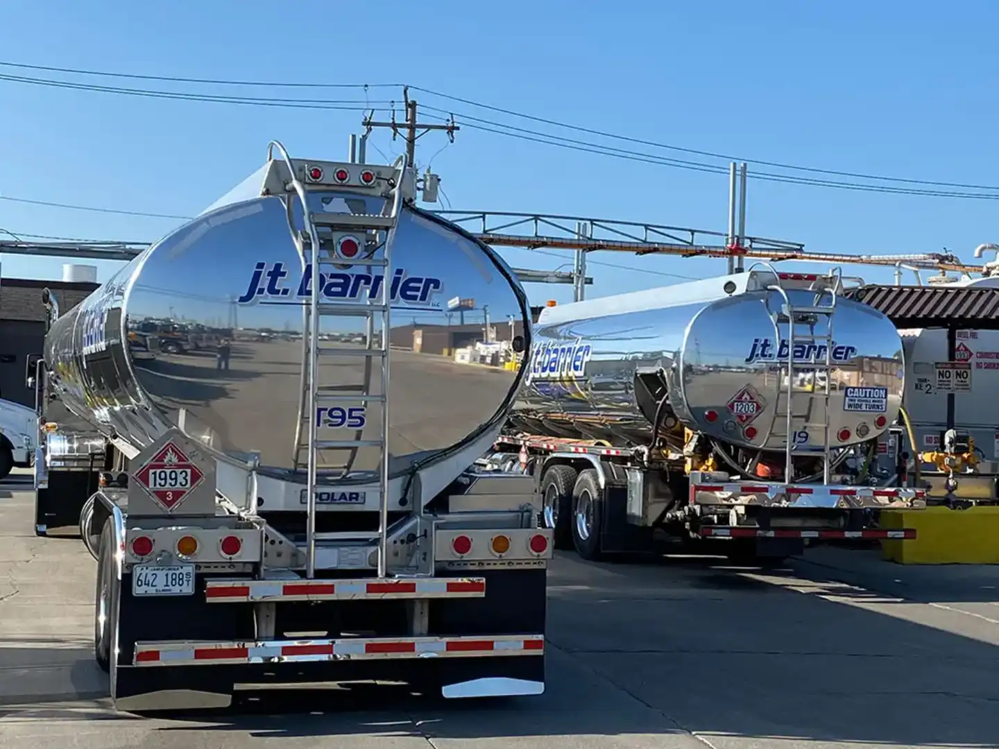 Two silver tank trucks parked in front of a building.