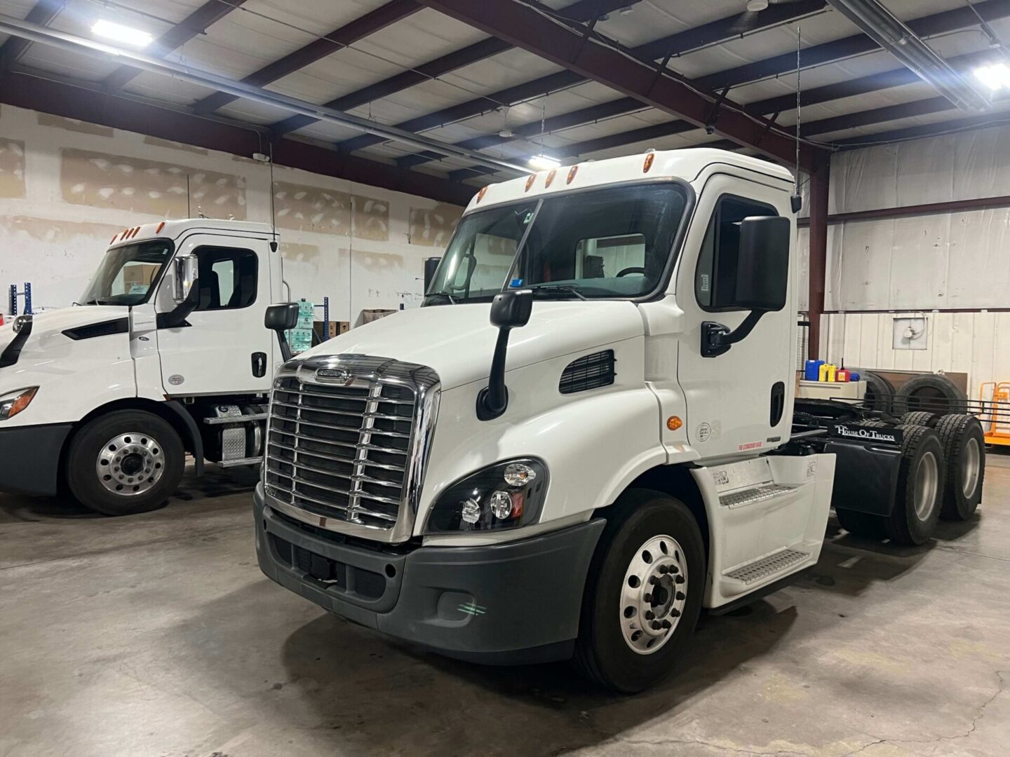 Two white trucks parked in a warehouse.