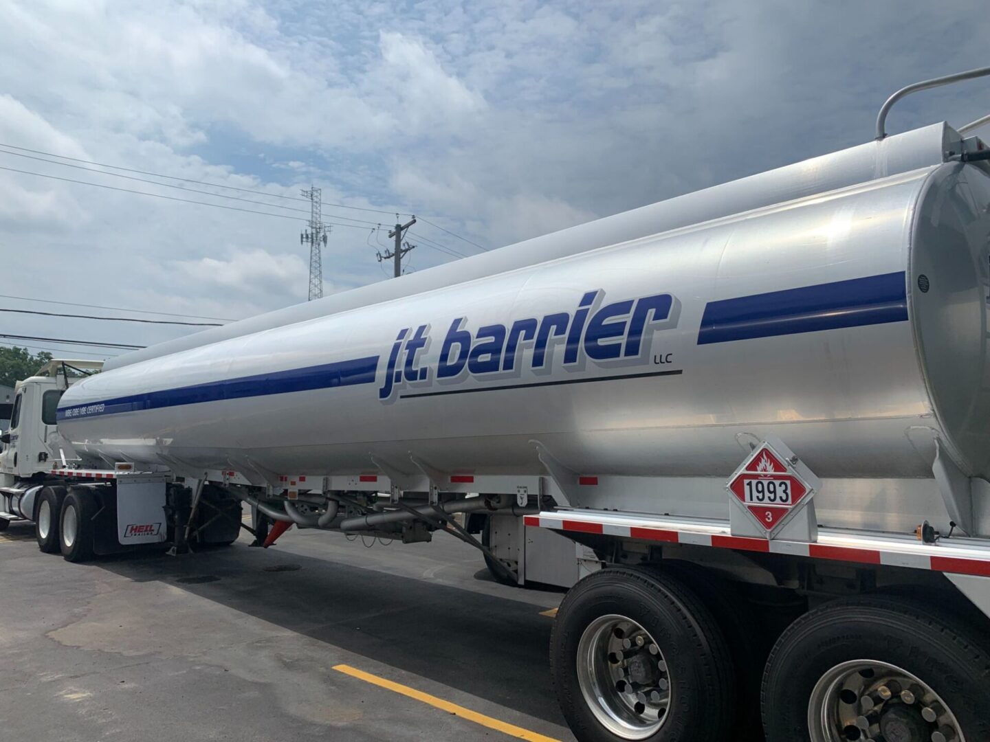 A white and blue tanker truck parked in a parking lot.