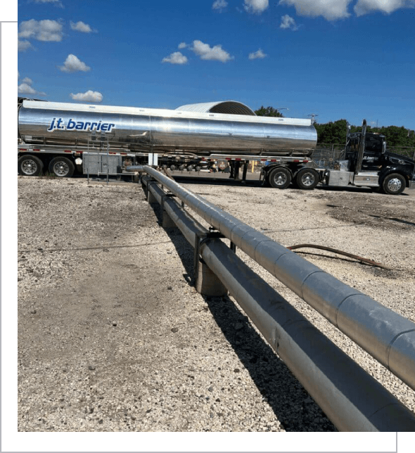 A tanker truck is parked next to a pipe.